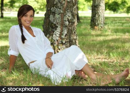 Woman dressed in white sat by tree