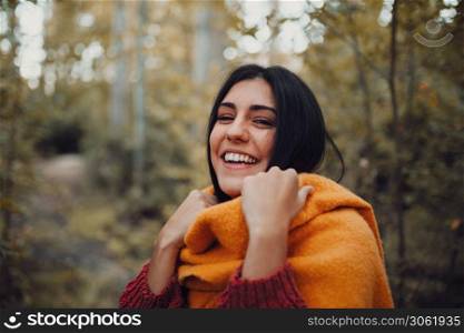 Woman dresses with her scarf inside the forest