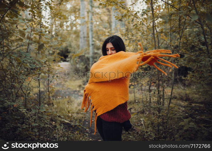 Woman dresses with her scarf inside the forest
