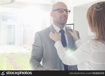 Woman dressing up businessman at home