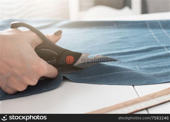 Woman dressmaker cutting fabric textile with scissors. Designer Cutting Fabric
