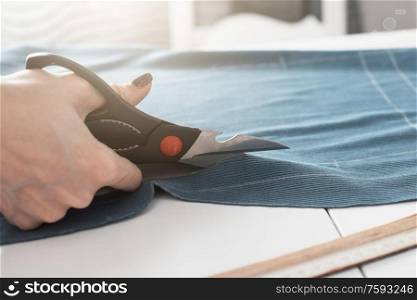 Woman dressmaker cutting fabric textile with scissors. Designer Cutting Fabric