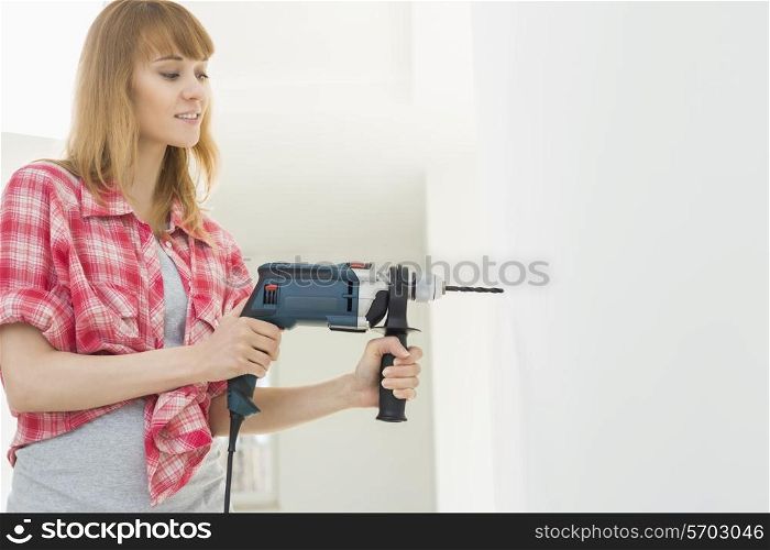 Woman drilling wall in new house