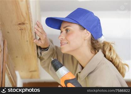 woman drilling wood plank indoors