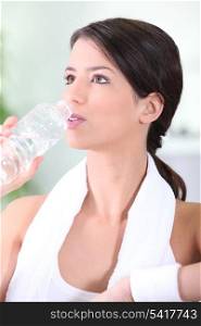 Woman drinking a bottle of water after a workout