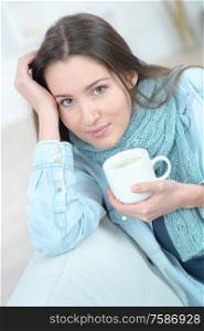 Woman drinking a cup of coffee on the sofa