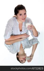 Woman drinking a glass of milk on a mirrored table