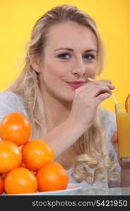 Woman drinking a glass of orange juice with a straw