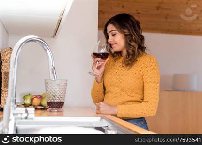 Woman drinking a glass of wine in a modern kitchen