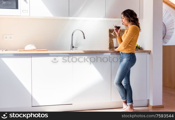 Woman drinking a glass of wine in a modern kitchen