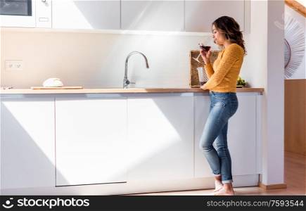 Woman drinking a glass of wine in a modern kitchen