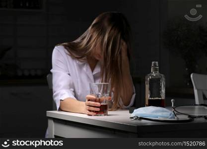 woman drinking alcohol in the kitchen. Young woman suffering from strong headache or migraine sitting with glass of whiskey in the kitchen. alcohol dependence. selective focus.. woman drinking alcohol in the kitchen. Young woman suffering from strong headache or migraine sitting with glass of whiskey in the kitchen. alcohol dependence. selective focus