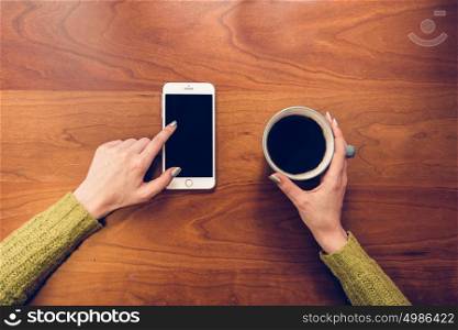 Woman drinking coffee and touching phone screen by finger.