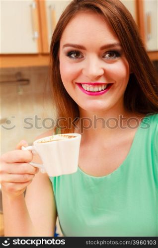 woman drinking coffee at home relaxing in kitchen.. Pretty woman drinking coffee at home. Gorgeous long haired girl with hot beverage relaxing in kitchen.