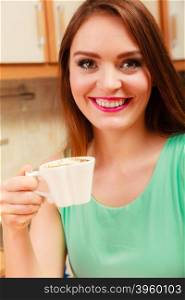 woman drinking coffee at home relaxing in kitchen.. Pretty woman drinking coffee at home. Gorgeous long haired girl with hot beverage relaxing in kitchen.