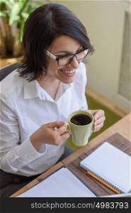 Woman drinking coffee while working at office