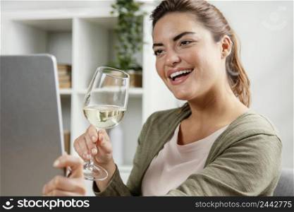 woman drinking glass wine while using laptop