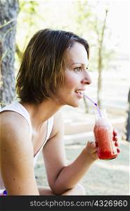 Woman drinking juice outdoors