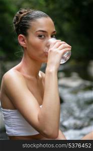 Woman drinking water by a brook
