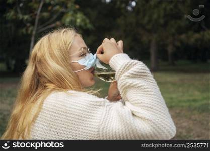 woman drinking wine while wearing face mask