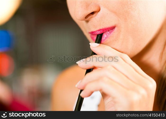 Woman drinking with a straw a drink which cannot be seen