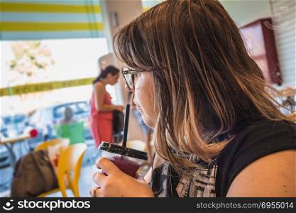 Woman drinks sweet shaved ice and looks away at ice cream parlor