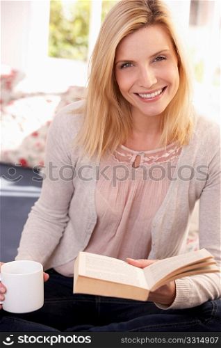 Woman drinks while reading book