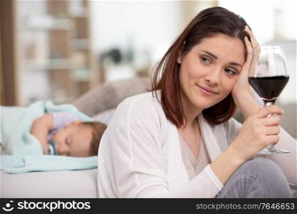 woman drinks wine while baby sleeps