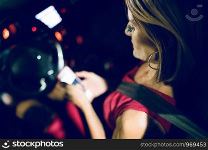 Woman driver sitting in her car automobile making call sending sms message using mobile phone