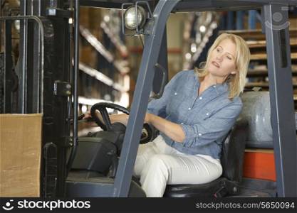 Woman Driving Fork Lift Truck In Warehouse