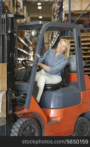 Woman Driving Fork Lift Truck In Warehouse