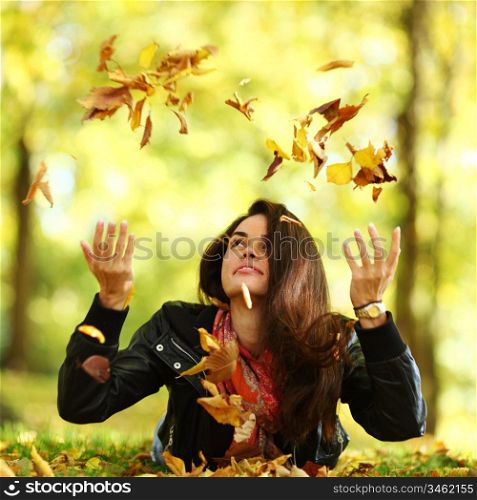 woman drop up leaves in autumn park