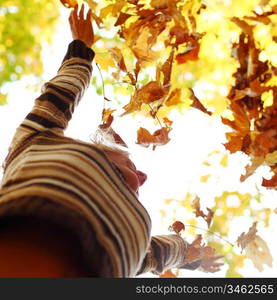 woman drop up leaves in autumn park