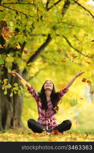 woman drop up leaves in autumn park