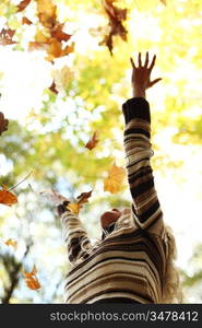 woman drop up leaves in autumn park