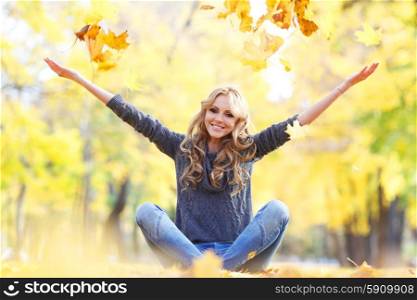 Woman drop up leaves. Woman drop up leaves sitting in autumn park