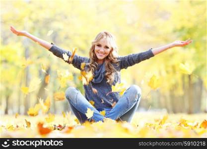 Woman drop up leaves. Woman drop up leaves sitting in autumn park