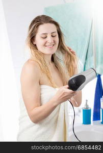 Woman drying hair in bathroom after having shower