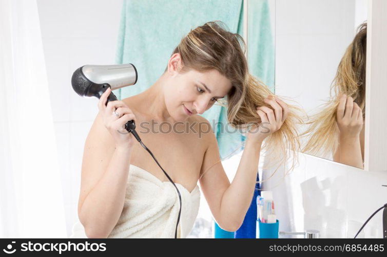 Woman drying hair with hairdryer after having bath