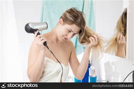 Woman drying hair with hairdryer after having bath
