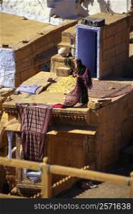 Woman drying sari on the roof of a house, Jaisalmer, Rajasthan, India
