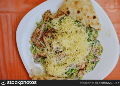 woman eat tasty chicken salad with fresh vegetables and cheese in retro kitchen