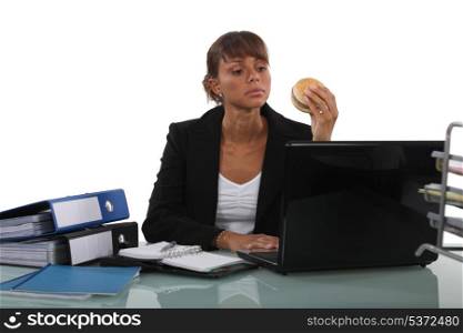 Woman eating a burger at her desk