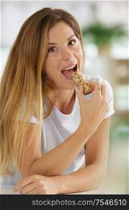 woman eating a cereal bar indoors