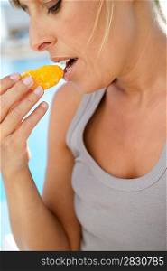 Woman eating an orange poolside