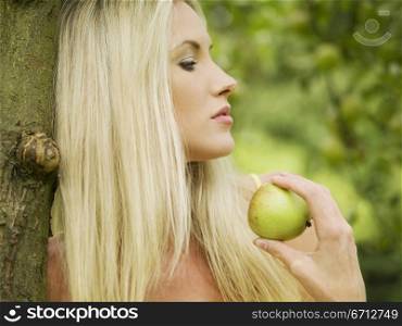 woman eating apple while leaning against tree