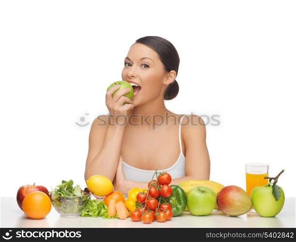 woman eating apple with lot of fruits and vegetables