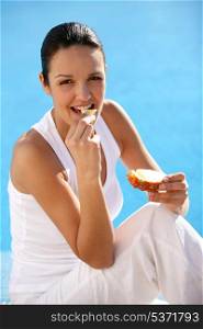 Woman eating bread at a poolside