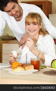 Woman eating breakfast while her affectionate boyfriend gazes at her