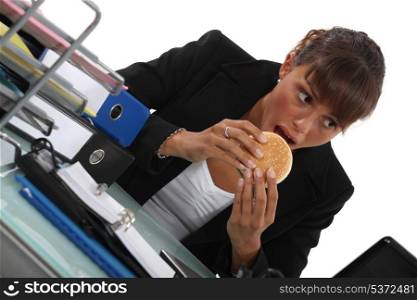 Woman eating burger at desk